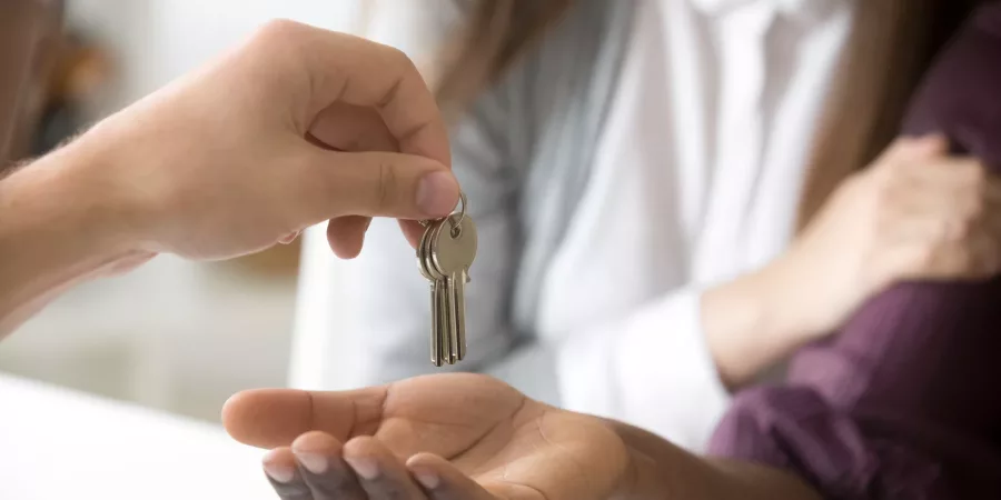 Real Estate Agent giving african customer taking keys to new home, interracial couple clients buying rental house, mortgage loan investment, real estate deal or property ownership concept, hands close up view